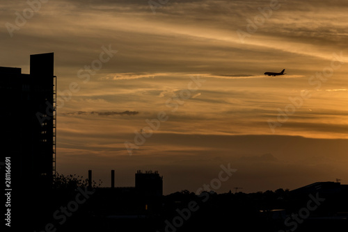 Silhouette of a plane at sunset in the city.