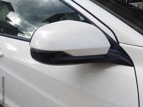 Side mirror of white car and black tinted glass