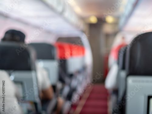 Blurred walkway between seats in economy class cabin on airplane.