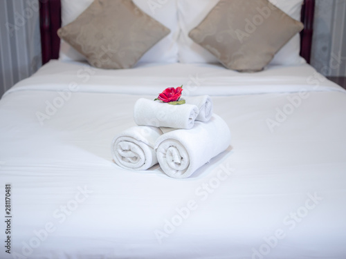 White towels decoration with red flower on white clean bed in hotel room.