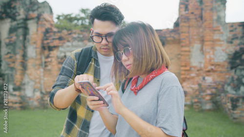 Traveler Asian couple using smartphone for direction and looking on location map while spending holiday trip at Ayutthaya, Thailand, backpacker sweet couple enjoy journey in traditional city.