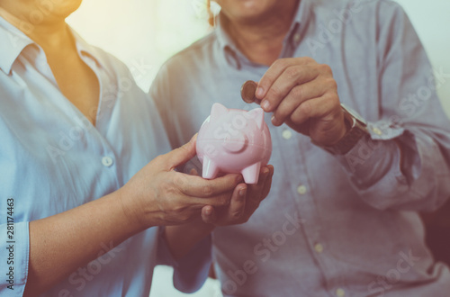 Senior couple hands putting coin to piggy bank for retirement together,Saving money concept