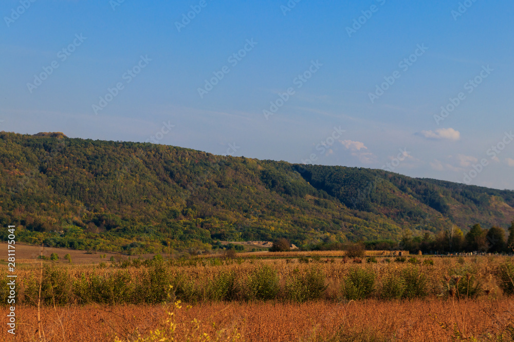 Picturesque autumn scenery with blue sky and colorful autumn trees on mountain hills