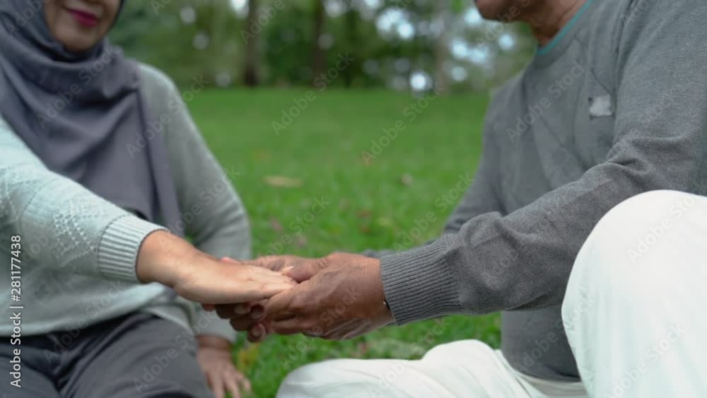 senior male massaging his wife on the palm after exercising in the park senior male massaging his wife on the palm after exercising in the park