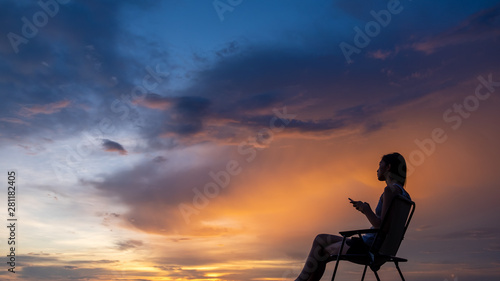 Young woman sitting on the view point at sunset background.