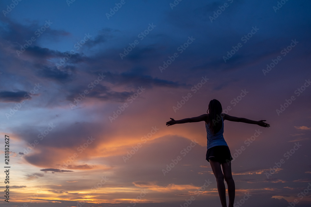 Fototapeta premium Silhouette of free woman enjoying freedom feeling happy at sunset. Serene relaxing woman in pure happiness