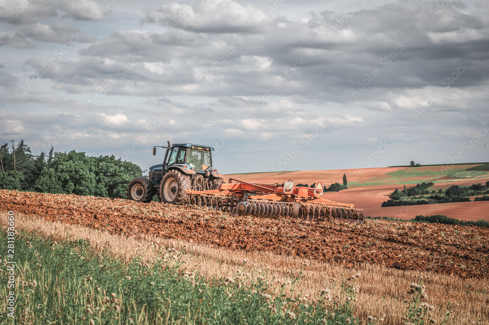 Fototapeta premium Farmer in tractor working on a field