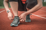 Woman is lacing her shoes on a stadium running track