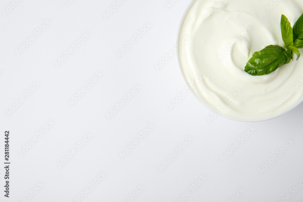 Bowl of fresh sour cream with basil on white background, top view Bowl of fresh sour cream with basil on white background, top view