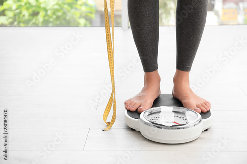 Foto Woman with tape standing on scales indoors, space for text