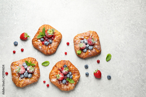 Fresh delicious puff pastry with sweet berries on light background, flat lay