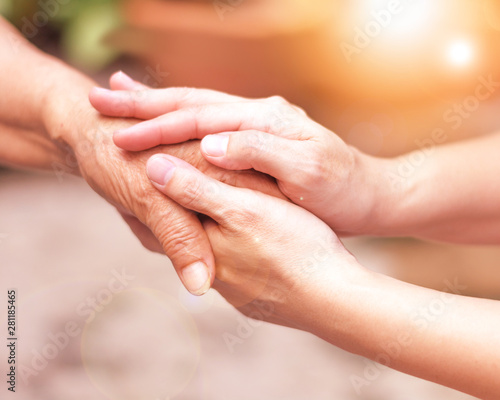Caregiver, carer hand holding elder hand in hospice care. Philanthropy kindness to disabled concept. photo