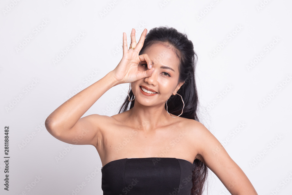Fototapeta premium Beautiful young Asian woman show OK sign over her eye.