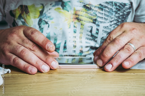 Mains d'un homme en train de poser une vitre de protection sur son téléphone
