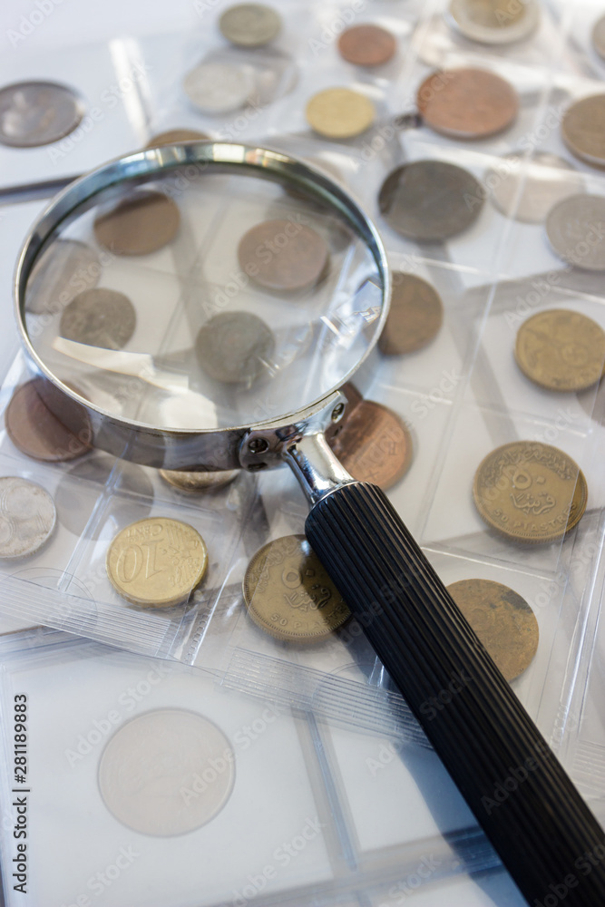 Different old collector's coins with a magnifying glass, blurred background Different old collector's coins with a magnifying glass, blurred background
