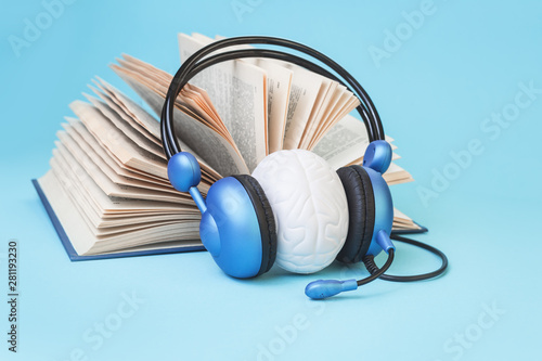 Open book and brain in headphones on blue. Listening practice or test, audio books dyslexia reading difficulty and disorder and auditory memory concept. Education and neurology with copy space