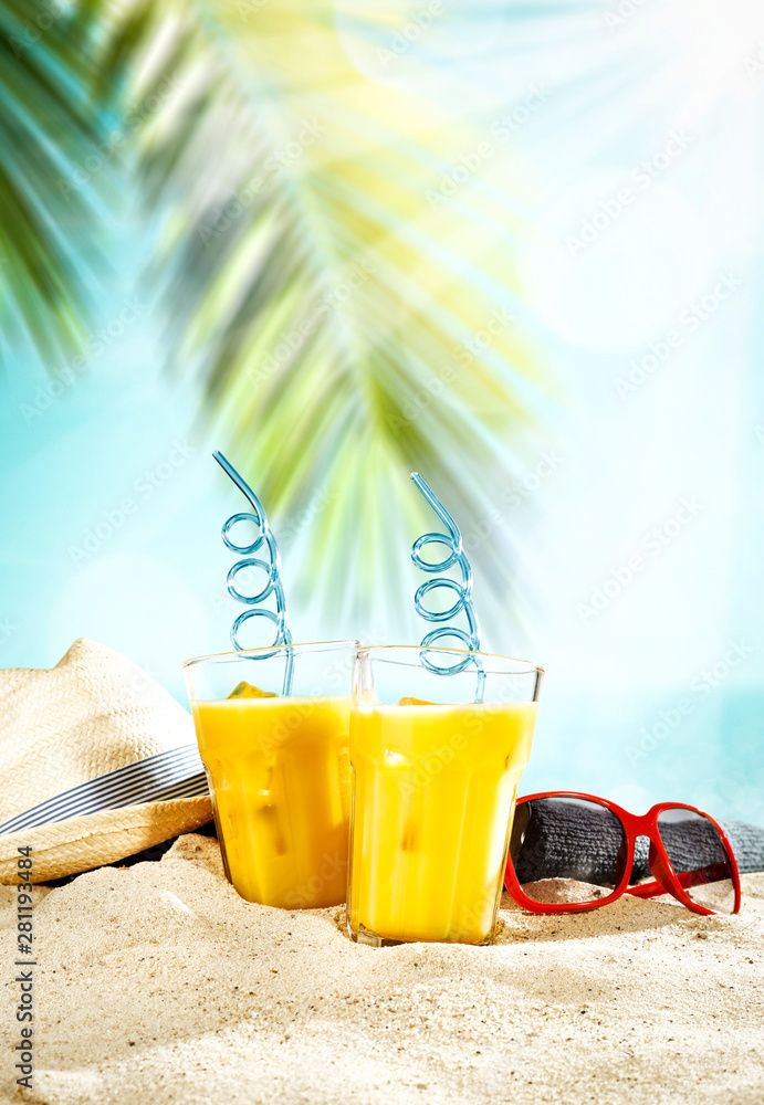 Table background with orange ice juice in a glass on a wooden table top with beautiful blue sky and ocean and palm tree view.