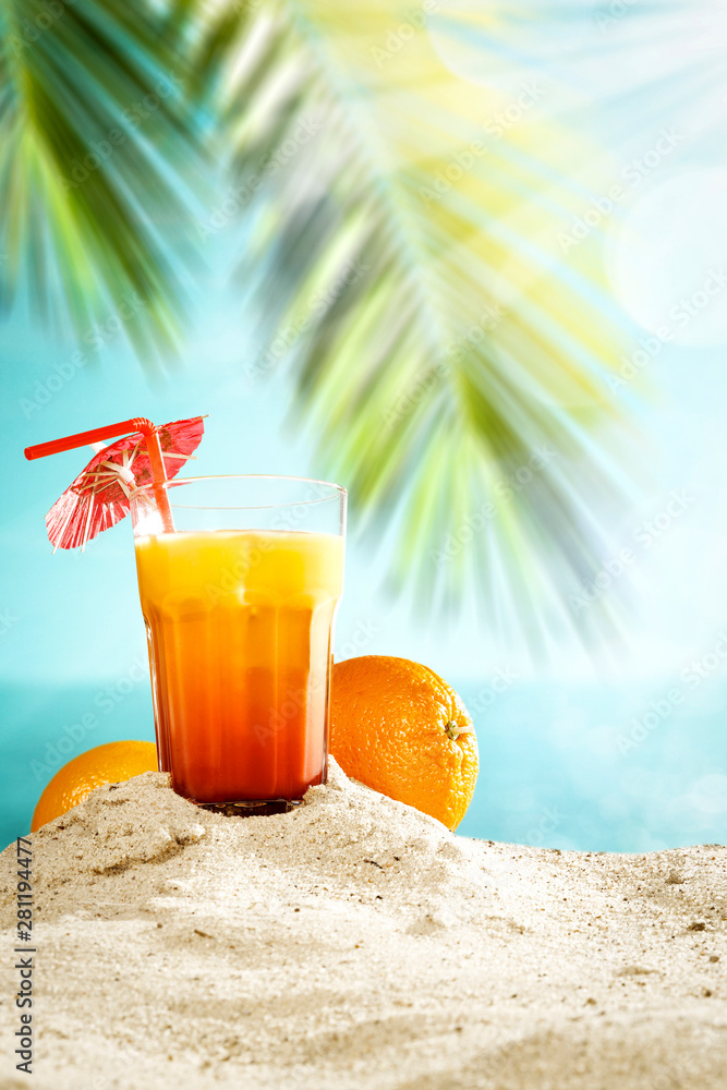 Table background with orange ice juice in a glass on a wooden table top with beautiful blue sky and ocean and palm tree view.