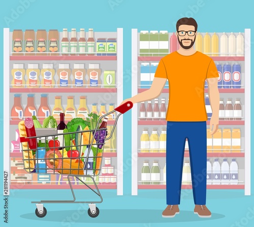 Young man pushing supermarket shopping cart full of groceries. Vector illustration in flat style