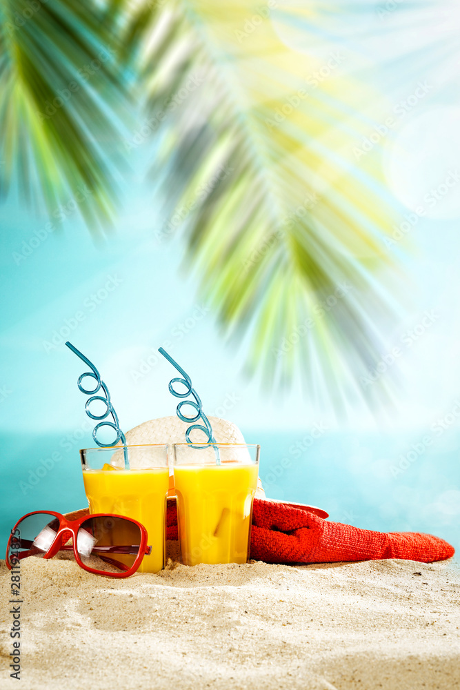 Fototapeta Stołowy tło z sokiem z lodu pomarańczowego w szkle na drewnianym blacie z pięknym widokiem na błękitne niebo, ocean i palmy.