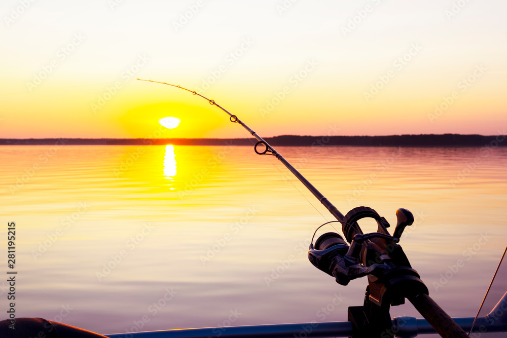 Fishing rod spinning with the line close-up. Fishing rod in rod holder in  fishing boat due the fishery day at the sunset. Fishing rod rings. Fishing  tackle. Fishing spinning reel. Stock Photo
