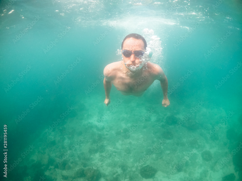 Naklejka premium Young man swimming in blue water in the ocean