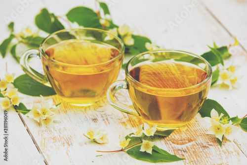 Two cups of green tea with jasmine flowers on grunge wooden table
