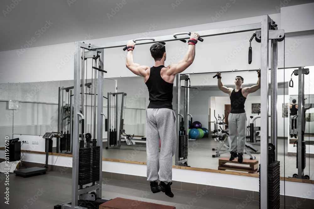 Fototapeta premium Man making some exercises on crossbar at gym