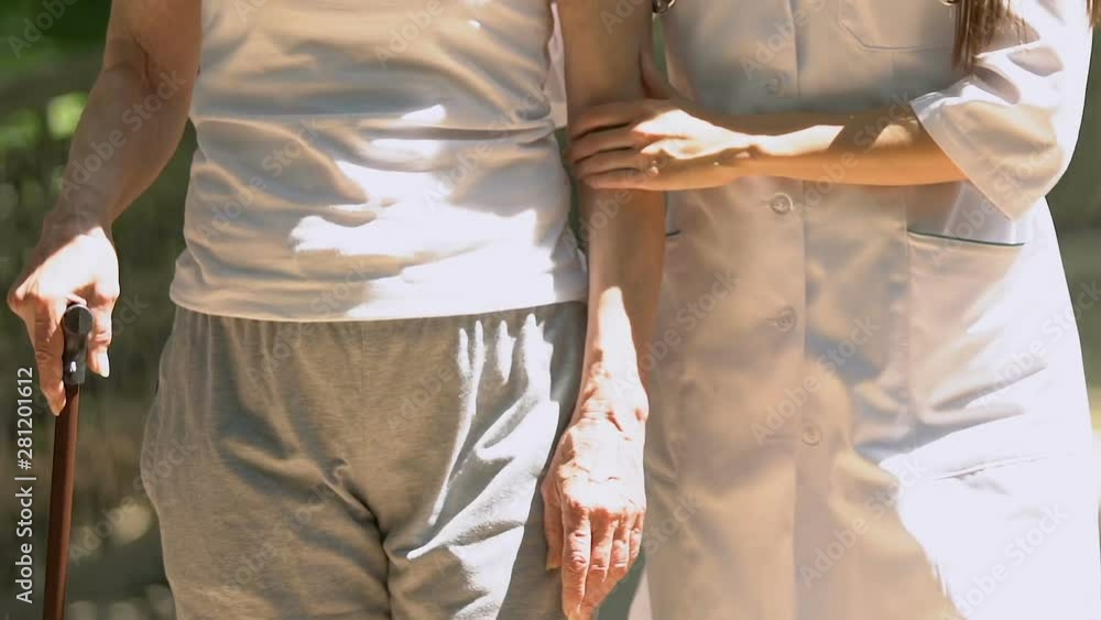 Caring nurse helping woman to move with walking stick, specializing hospital Caring nurse helping woman to move with walking stick, specializing hospital
