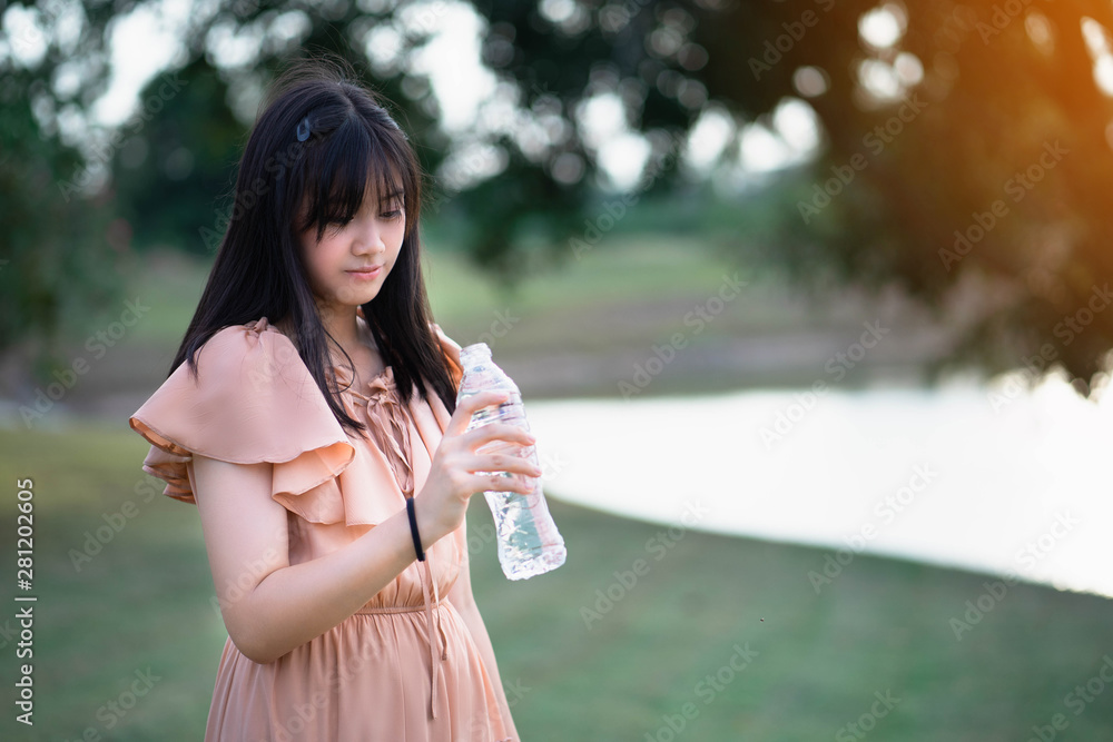 Portrait of beautiful girl drinking cold water in the park, A beautiful girl is holding a bottle of water. Portrait of beautiful girl drinking cold water in the park, A beautiful girl is holding a bottle of water.