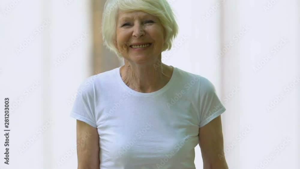 Senior woman with walking frame smiling at camera in hospital park, recovery Senior woman with walking frame smiling at camera in hospital park, recovery