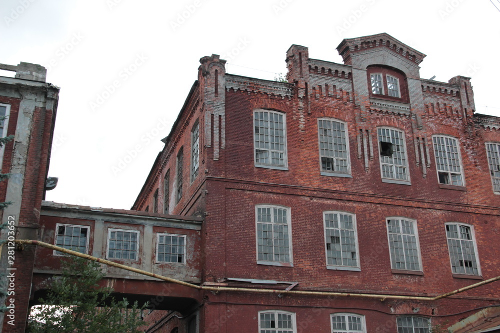 Fototapeta premium Abandoned red brick old textile fabric in Ivanovo with background of cloudy sky