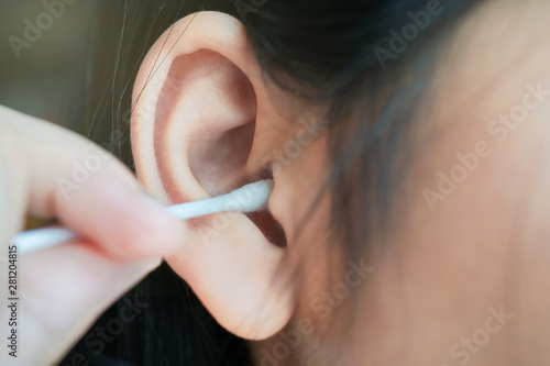 closeup of cotton bud into girl's ear for cleaning