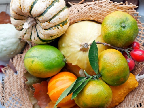  Bright ripe tangerines and pumpkins in a straw basket, concept of autumn harvest, healthy nutrition