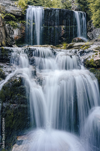 Waterfall photograph. Long exposure photo of a beautiful waterfall of Jedlova  Jizerske mountains  Czechia. Motion blurr water in a mountain creek in a deep forest. Alaska like stream with a rocks.