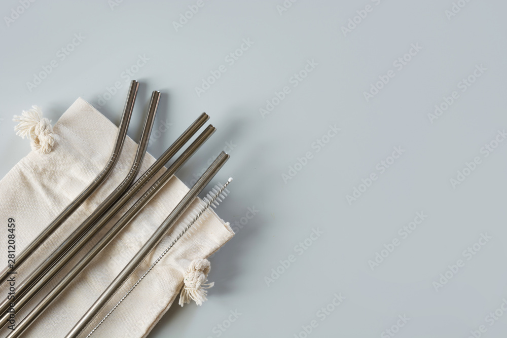 Eco natural metallic straws with cotton bag on grey. Sustainable lifestyle concept. Zero waste, plastic free. Pollution environment. Eco natural metallic straws with cotton bag on grey. Sustainable lifestyle concept. Zero waste, plastic free. Pollution environment.