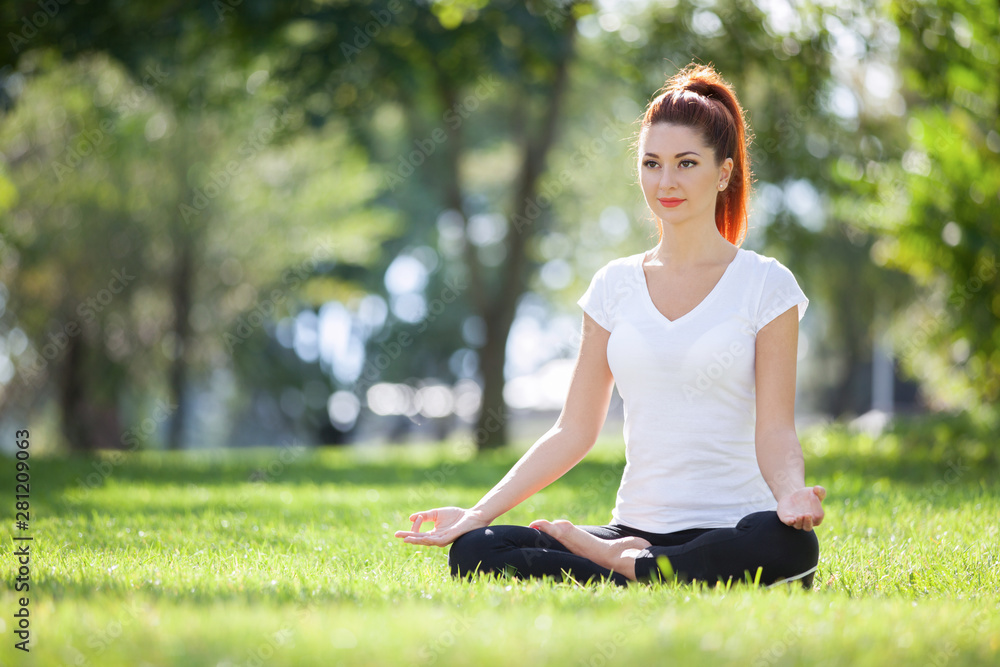 Yoga outdoor. Happy woman doing yoga exercises, meditate in the park. Yoga meditation in nature. Concept of healthy lifestyle and relaxation. Pretty woman practicing yoga on the grass Yoga outdoor. Happy woman doing yoga exercises, meditate in the park. Yoga meditation in nature. Concept of healthy lifestyle and relaxation. Pretty woman practicing yoga on the grass