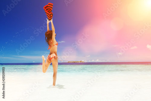 Happy young woman jumping on the sunny beach. Happy lifestyle. White sand, blue sky and crystal sea of tropical beach. Vacation at Paradise. Ocean beach relax, travel to islands