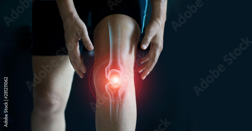 Elderly woman suffering from pain in knee. Tendon problems and Joint inflammation on dark background. photo