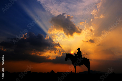 The silhouette of a cowboy on horseback at sunset on a  background