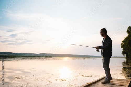 Young man fishing at misty sunrise