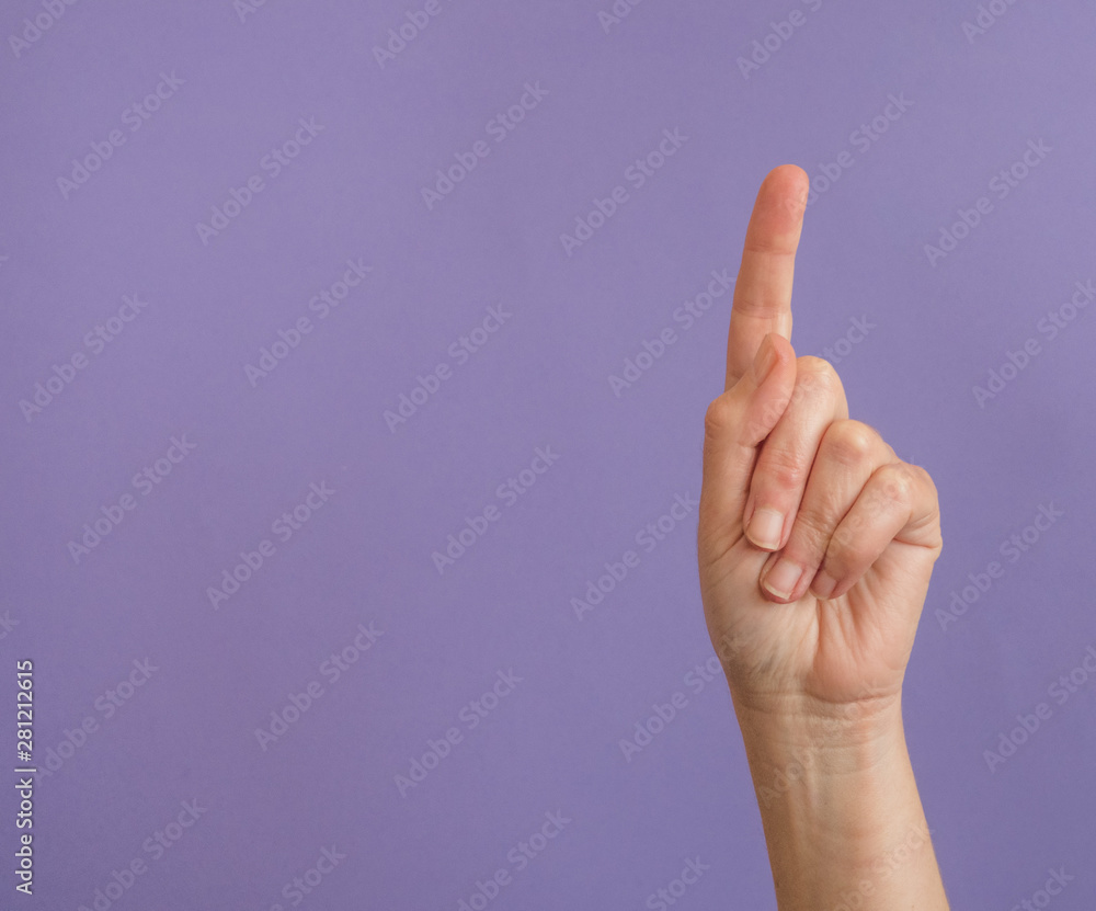 Hand with raised index finger on purple background with copy space