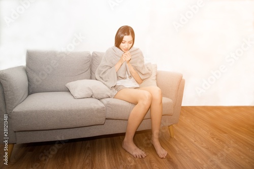 Asian woman sad suffering from cold Due to fever on the sofa in the room..