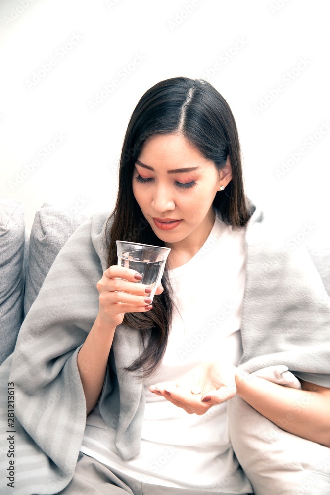 Asian young woman wrapped in a blanket and during illness and taking antipyretics.. Asian young woman wrapped in a blanket and during illness and taking antipyretics..