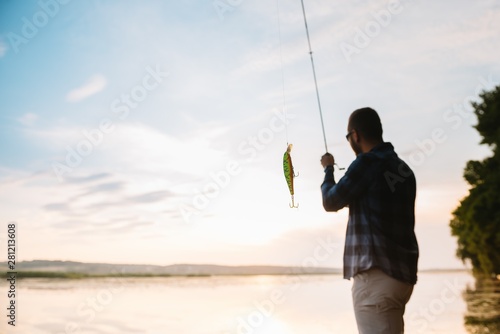 Young man fishing at misty sunrise