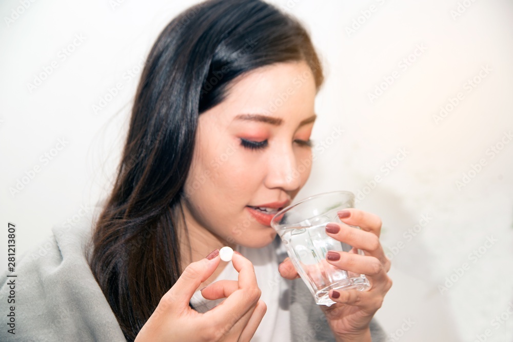 Asian young woman wrapped in a blanket and during illness and taking antipyretics.. Asian young woman wrapped in a blanket and during illness and taking antipyretics..