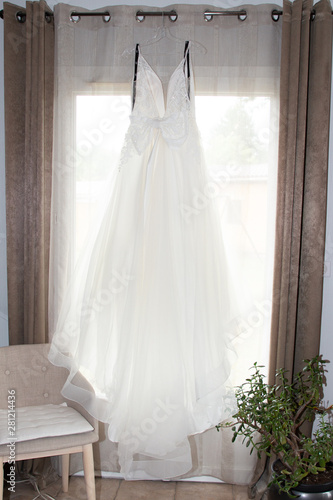 white wedding dress hanging on a window