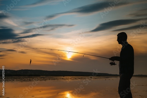 A fisherman silhouette fishing at sunset. Freshwater fishing, catch of fish