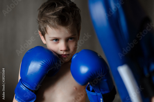 serious boy in Boxing gloves fulfills blow. a little man engaged in sports since childhood © Nataliia