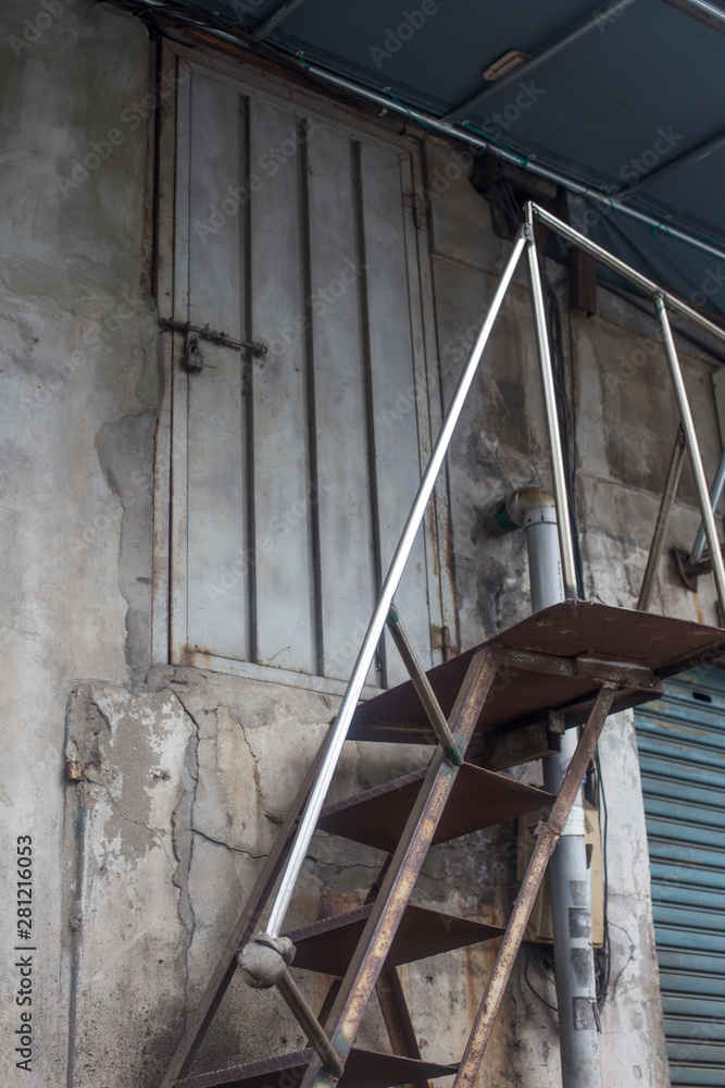 Iron staircase with a vintage iron door. iron door in the concrete wall and iron escape ladder